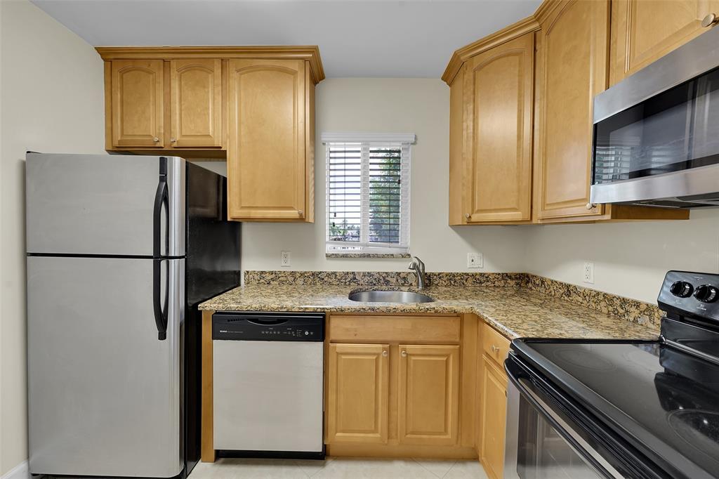 410 Southwest 15th Street, Unit 103 Pompano Beach, FL 33060 - Photo 8 of 16 a kitchen with stainless steel appliances granite countertop a sink stove and refrigerator