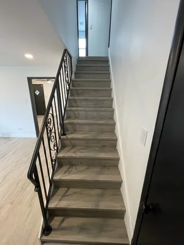 a view of a hallway with wooden floor and staircase