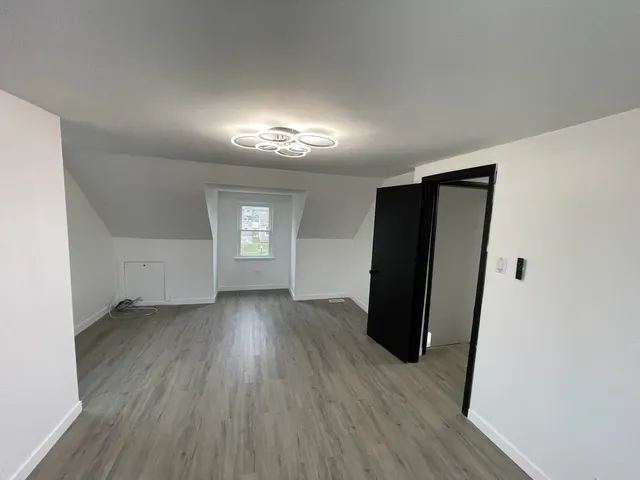 a view of a hallway with wooden floor and a bathroom