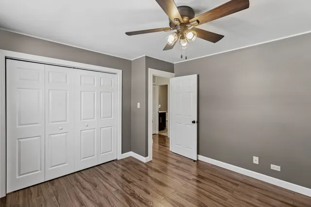 an empty room with wooden floor and ceiling fan