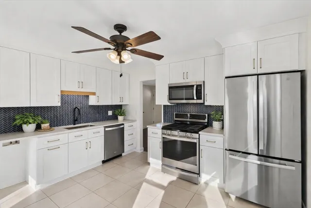 a kitchen with white cabinets stainless steel appliances and a counter space