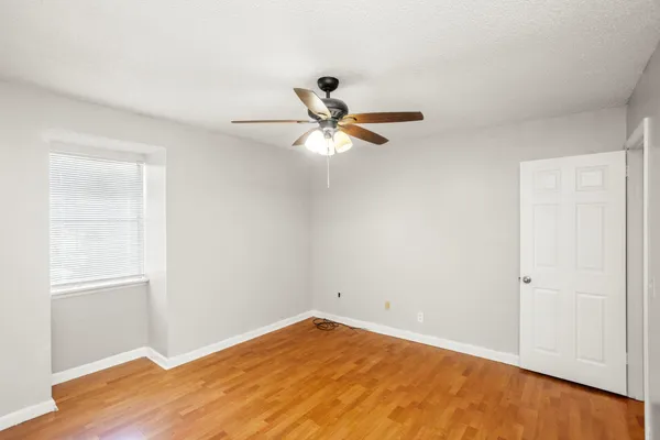 an empty room with a window and a ceiling fan