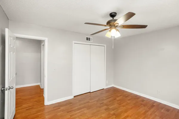 a view of empty room with wooden floor and fan