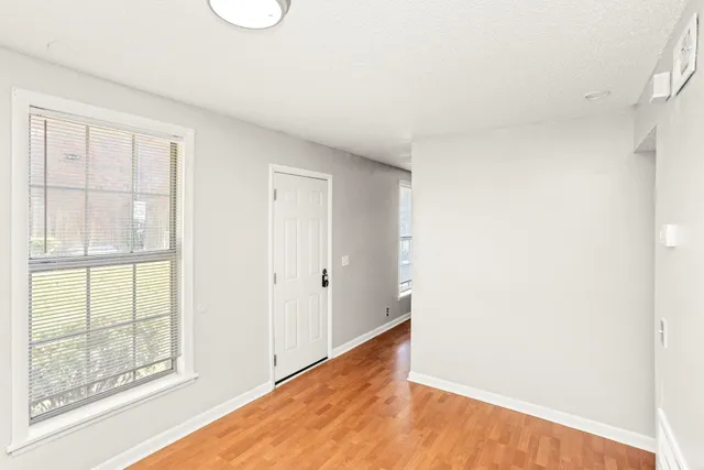 a view of an empty room with wooden floor and a window