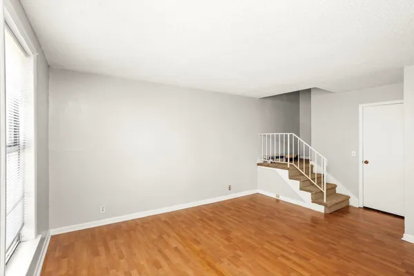 a view of an empty room with wooden floor and stairs