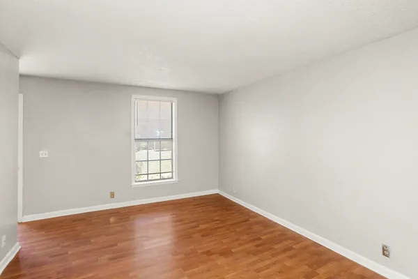 an empty room with wooden floor and window