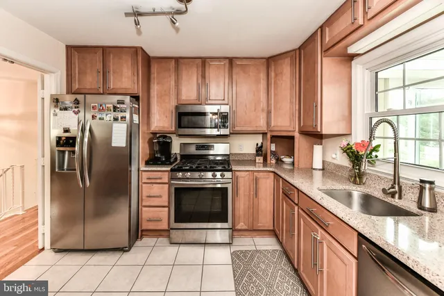 a kitchen with stainless steel appliances granite countertop a refrigerator a sink a stove a washer dryer and cabinets