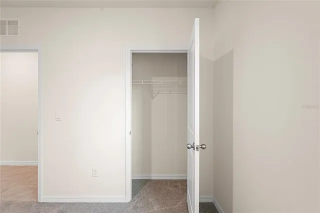 a view of a white house next to a yard with potted plants