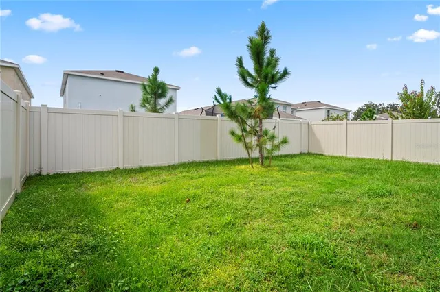 an aerial view of a residential houses with outdoor space and trees