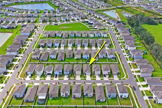 an aerial view of residential houses with outdoor space and trees
