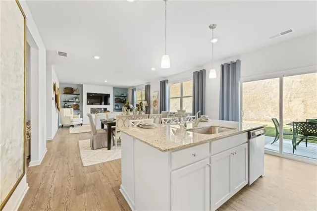 a open dining hall with stainless steel appliances granite countertop a sink dishwasher a dining table and chairs with wooden floor