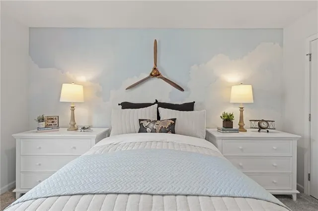 a bedroom with a bed and a lamp on dresser