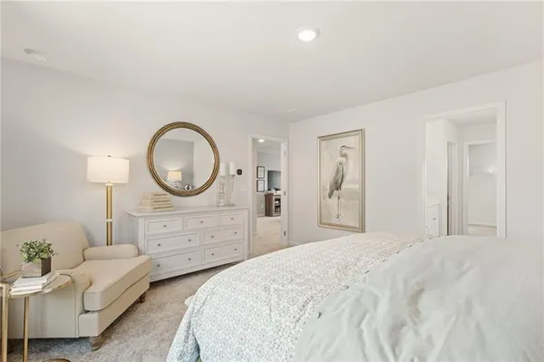 a bedroom with a bed a mirror and lamp on dresser
