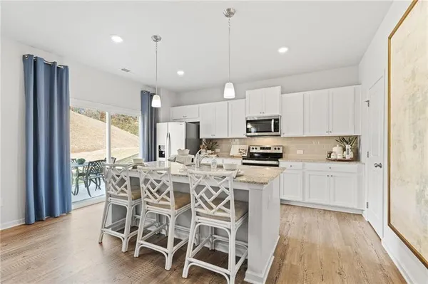 a kitchen with stainless steel appliances granite countertop a stove top oven a refrigerator with white cabinets and wooden floor