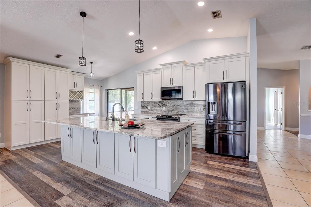 1418 Buckner Road Valrico, FL 33596 - Photo 18 of 37 a kitchen with stainless steel appliances kitchen island granite countertop a refrigerator stove and oven