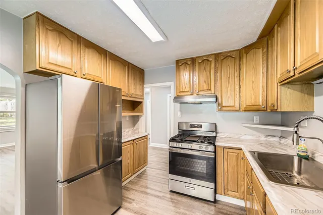 a kitchen with granite countertop a refrigerator stove and sink