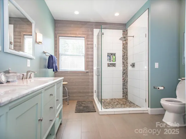 a bathroom with a granite countertop sink a toilet a shower and a mirror