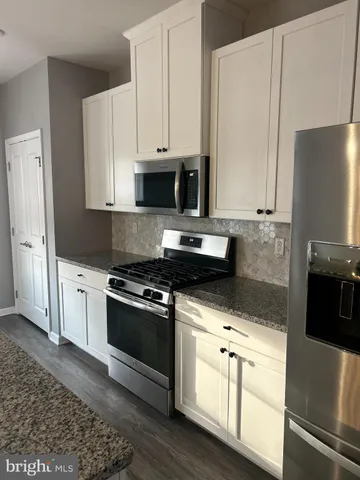 a kitchen with stainless steel appliances granite countertop a kitchen island a stove a table and chair