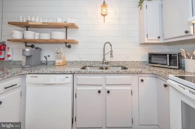 a kitchen with stainless steel appliances granite countertop white cabinets and a sink