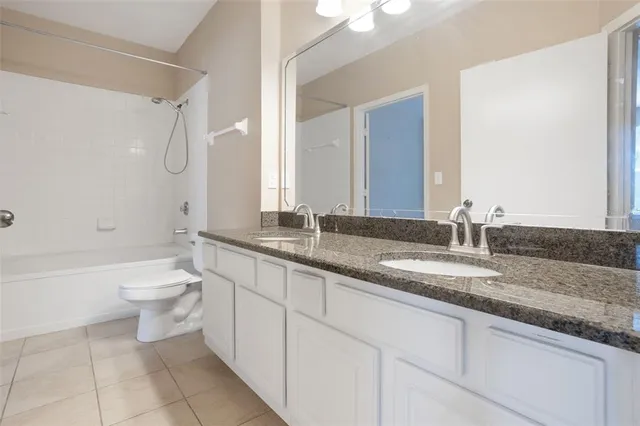 a bathroom with a granite countertop sink a toilet and bathtub