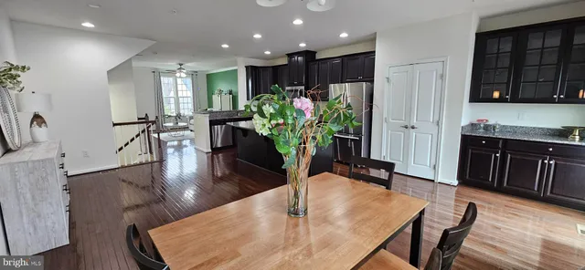 a room with stainless steel appliances furniture wooden floor and a view of kitchen