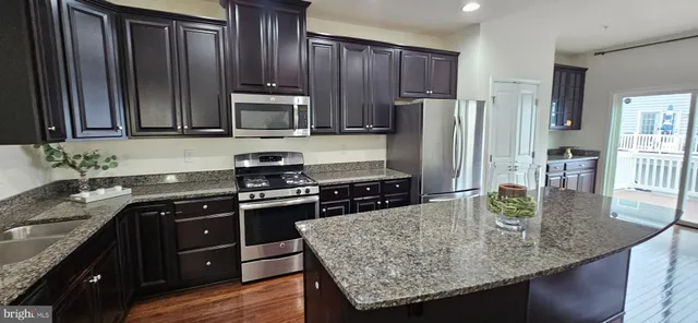 a kitchen with stainless steel appliances granite countertop a sink refrigerator and microwave