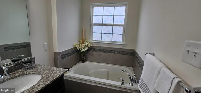 a bathroom with a granite countertop tub sink and mirror