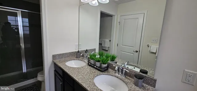 a bathroom with a granite countertop sink a mirror and shower