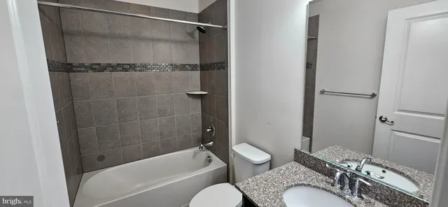 a bathroom with a granite countertop bathtub shower sink and toilet
