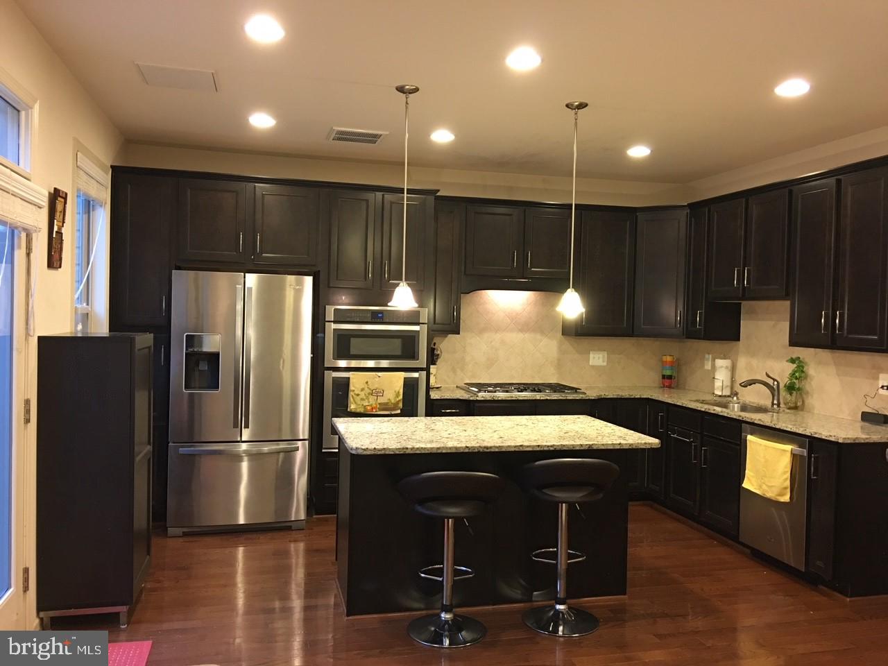 23337 Tradewind Drive Ashburn, VA 20148 - Photo 5 of 28 a kitchen with kitchen island granite countertop wooden cabinets and stainless steel appliances