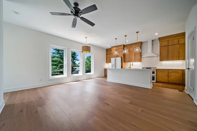 a view of a kitchen with furniture a ceiling fan and wooden floor