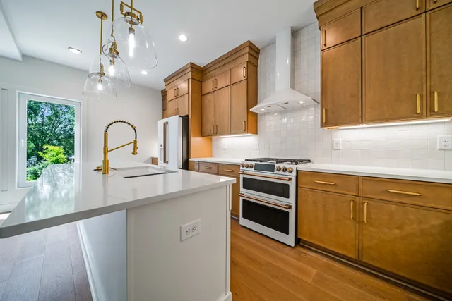a kitchen with stainless steel appliances granite countertop a stove a sink dishwasher and microwave with wooden floor