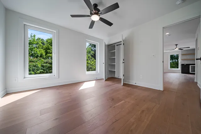 a view of an empty room with window and wooden floor