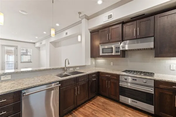 a kitchen with stainless steel appliances granite countertop wooden cabinets stove top oven and sink
