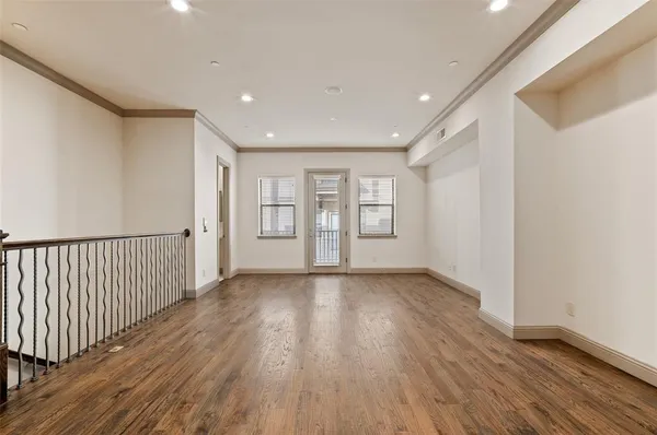 a view of an empty room with wooden floor and windows