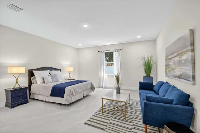 a spacious bedroom with a bed a couch and potted plant in it