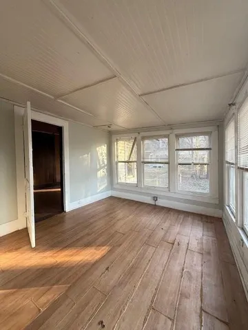 a view of an empty room with window and wooden floor