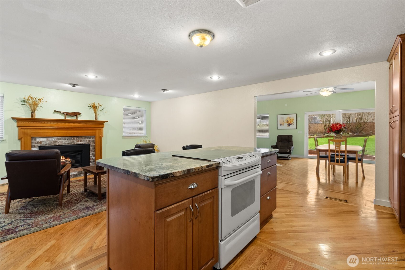 1105 Irving Street Southwest Tumwater, WA 98512 - Photo 11 of 38 a kitchen with stainless steel appliances granite countertop a stove top oven a dining table and chairs with wooden floor