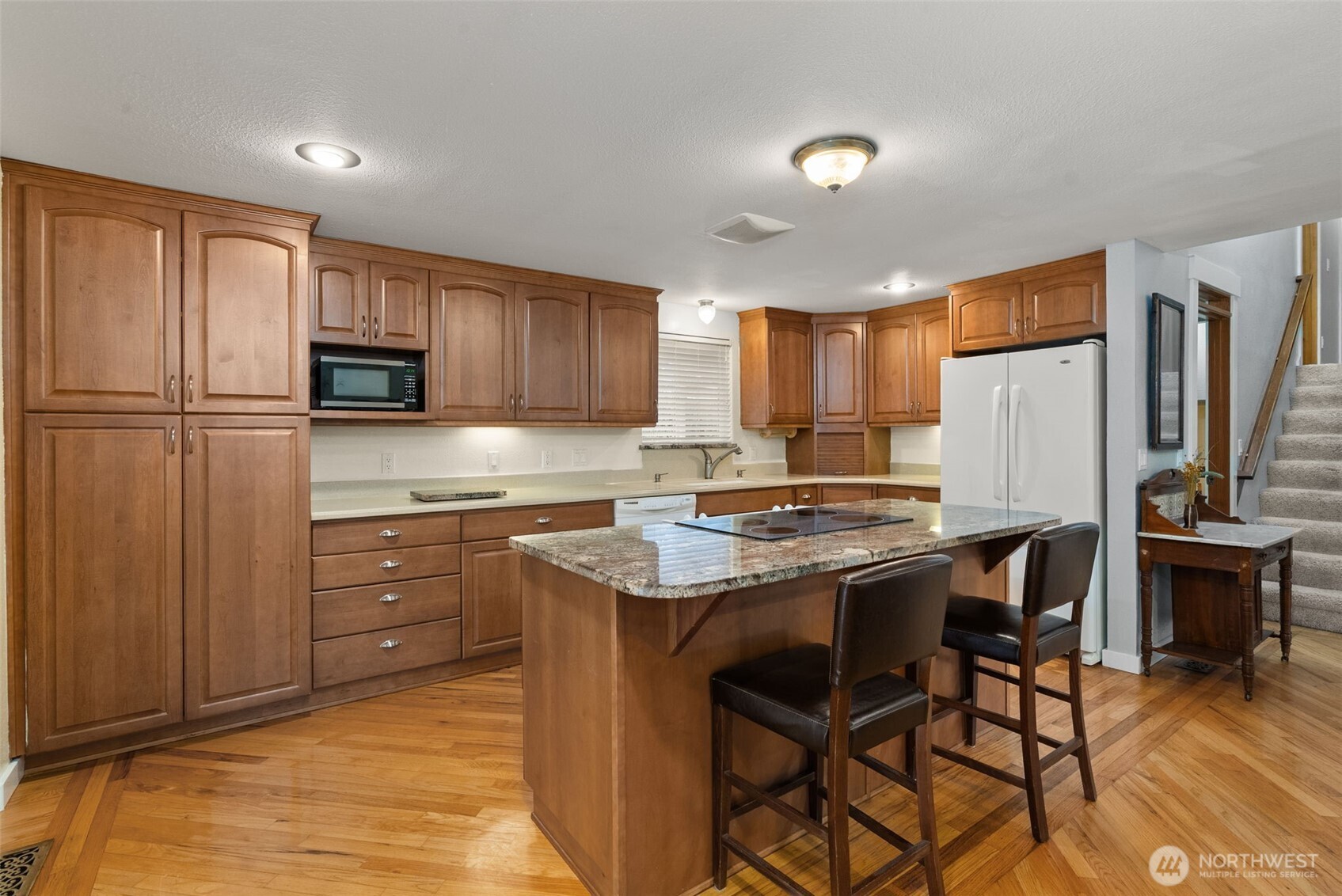 1105 Irving Street Southwest Tumwater, WA 98512 - Photo 9 of 38 a kitchen with kitchen island granite countertop wooden cabinets a stove a sink and a refrigerator with wooden floor