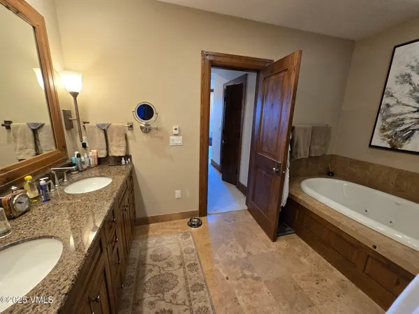a bathroom with a granite countertop tub sink and mirror