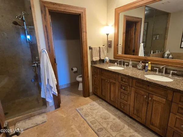 a spacious bathroom with a double vanity sink a mirror and a shower