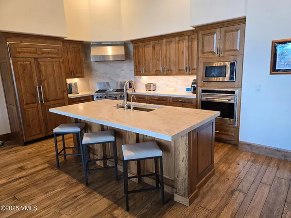 a kitchen with stainless steel appliances wooden floor dining table and chairs