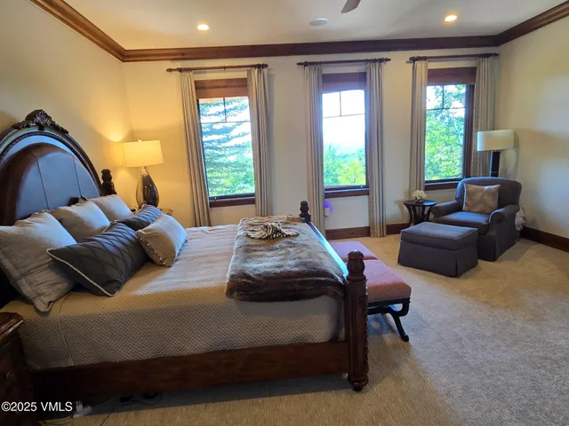 a bedroom with a bed couch and two large window