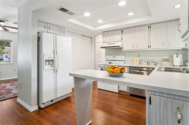 a kitchen with a sink a stove a dining table chairs and view living room