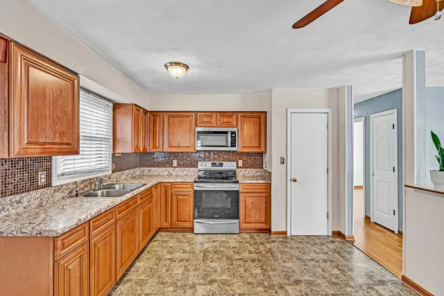 a kitchen with stainless steel appliances granite countertop a stove a sink and a refrigerator