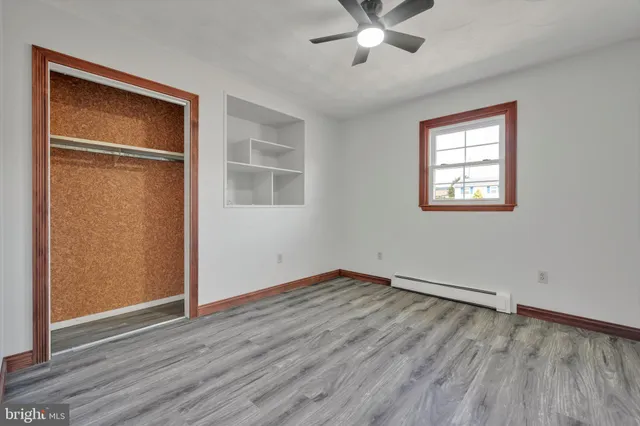 an empty room with wooden floor closet and windows