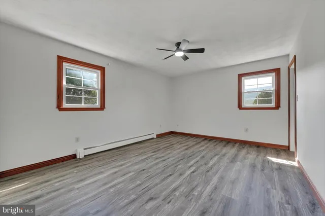 a view of empty room with wooden floor and fan
