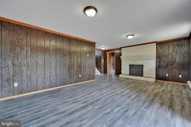 an empty room with wooden floor and fireplace