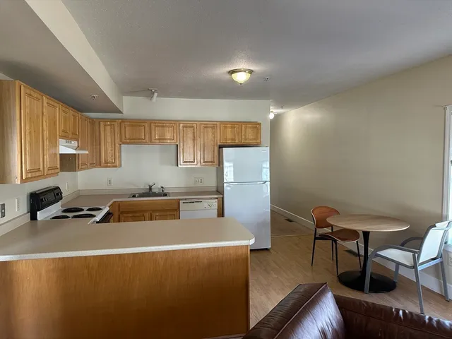 a kitchen with stainless steel appliances a stove a sink a refrigerator white cabinets and wooden floor