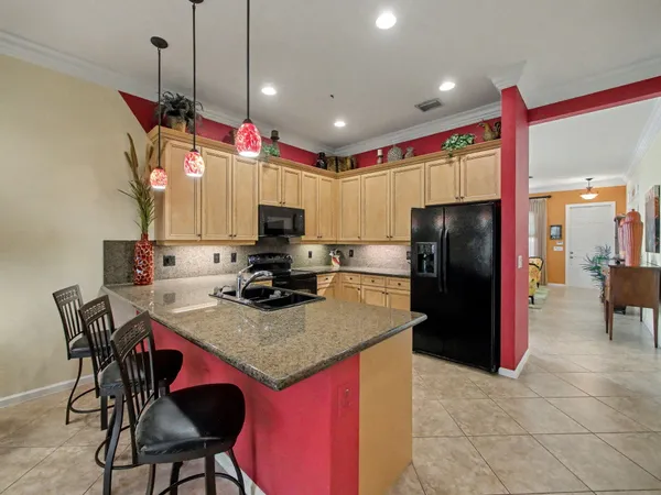 a kitchen with stainless steel appliances granite countertop a refrigerator a sink dishwasher and a stove with a dining table